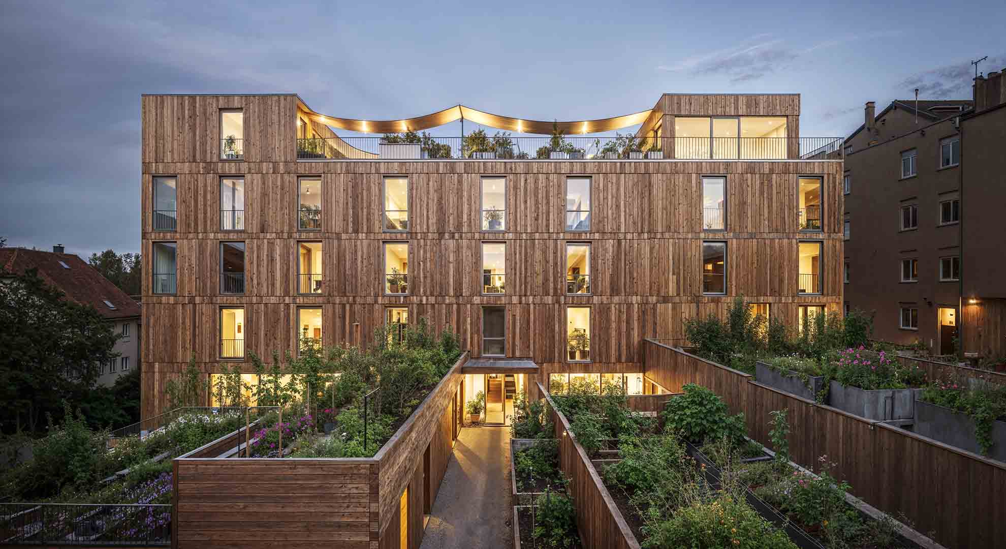 Wooden facade and planted terraces of a development at dusk